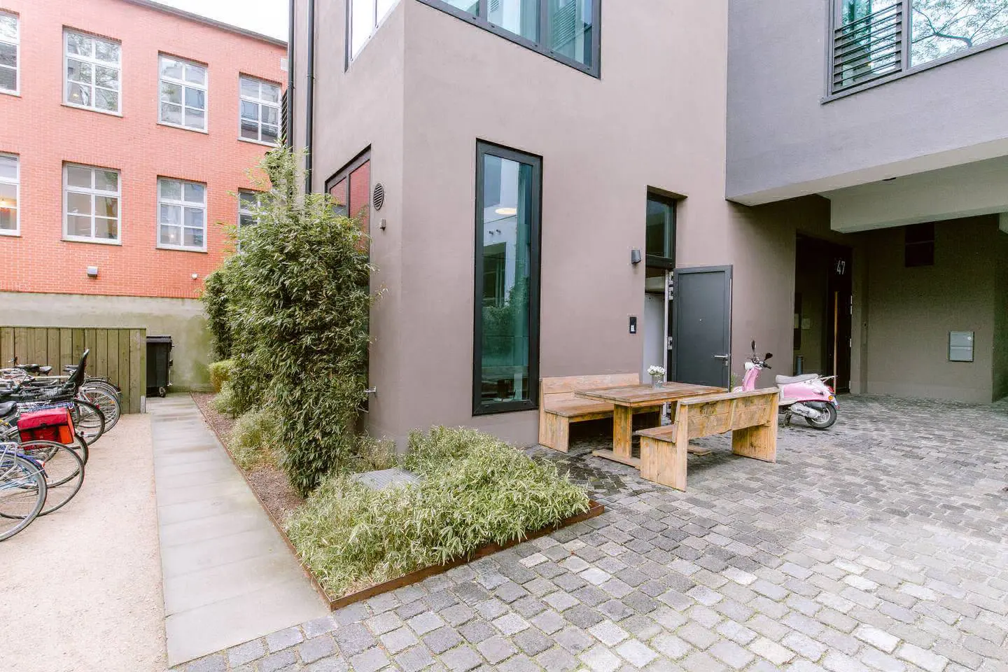 Innenhof des Stadtlofts mit Kopfsteinpflaster, Holzbank, Bambus und Fahrradständern