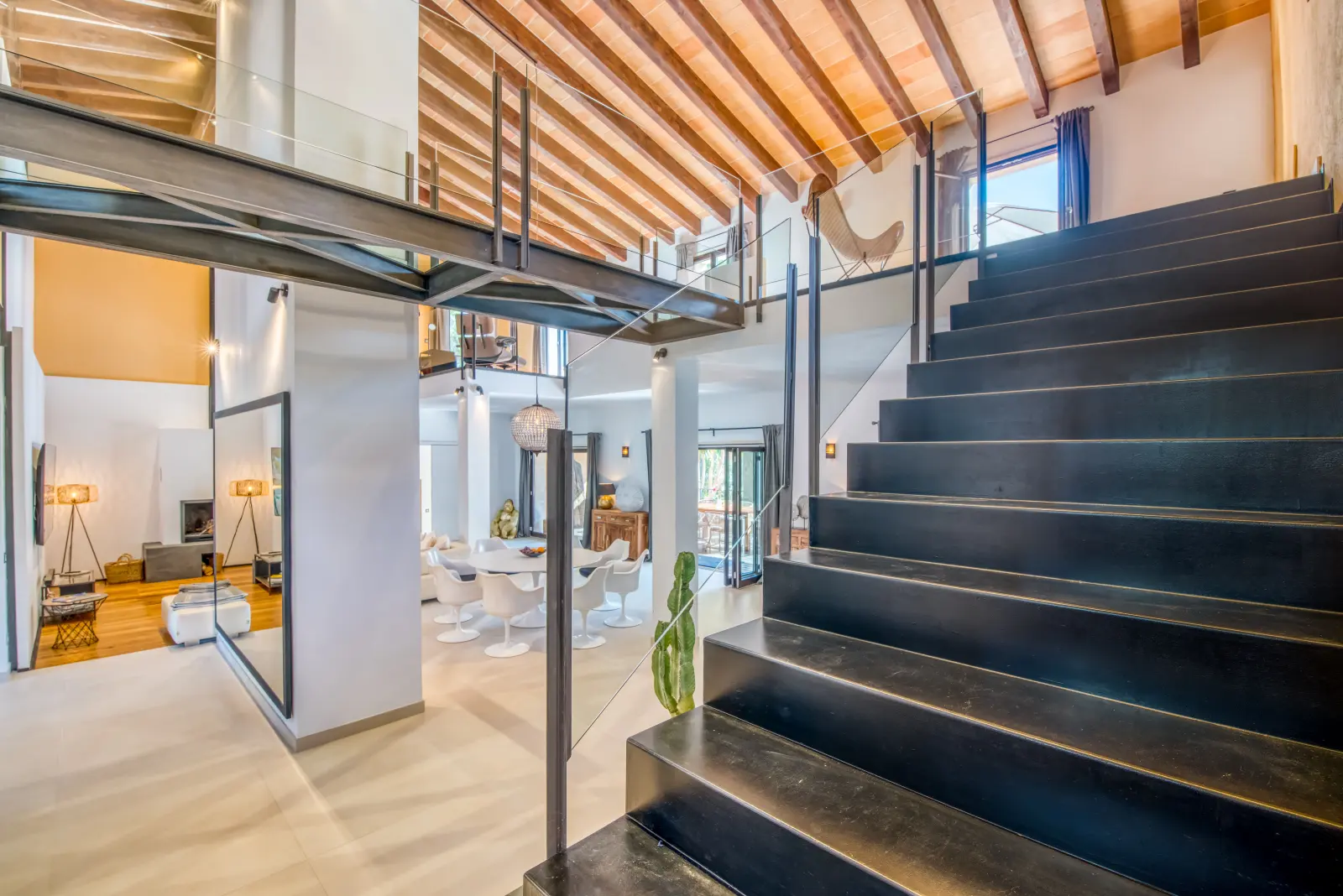 Schwarze Treppe, Holzbalkendecke und Blick in den offenen Wohnraum