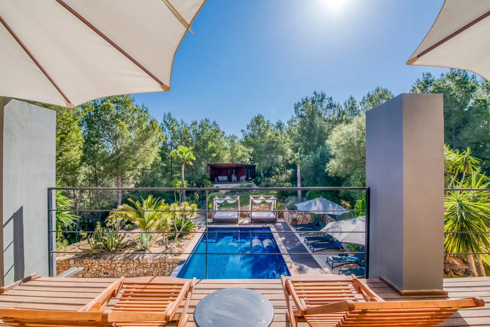 Sonnenliegen auf der Terrasse mit Blick auf den Pool und die Pinien