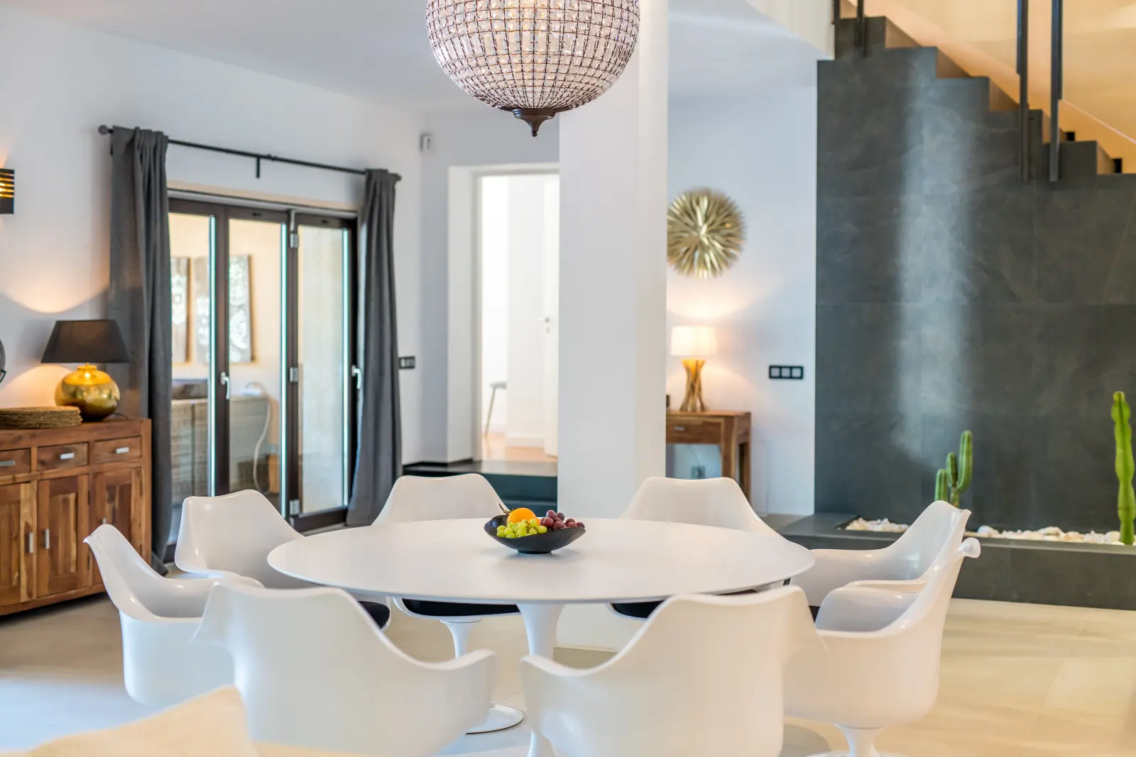 Weißer Tulip-Esstisch mit Stühlen, Kronleuchter und Treppe im Wohnraum