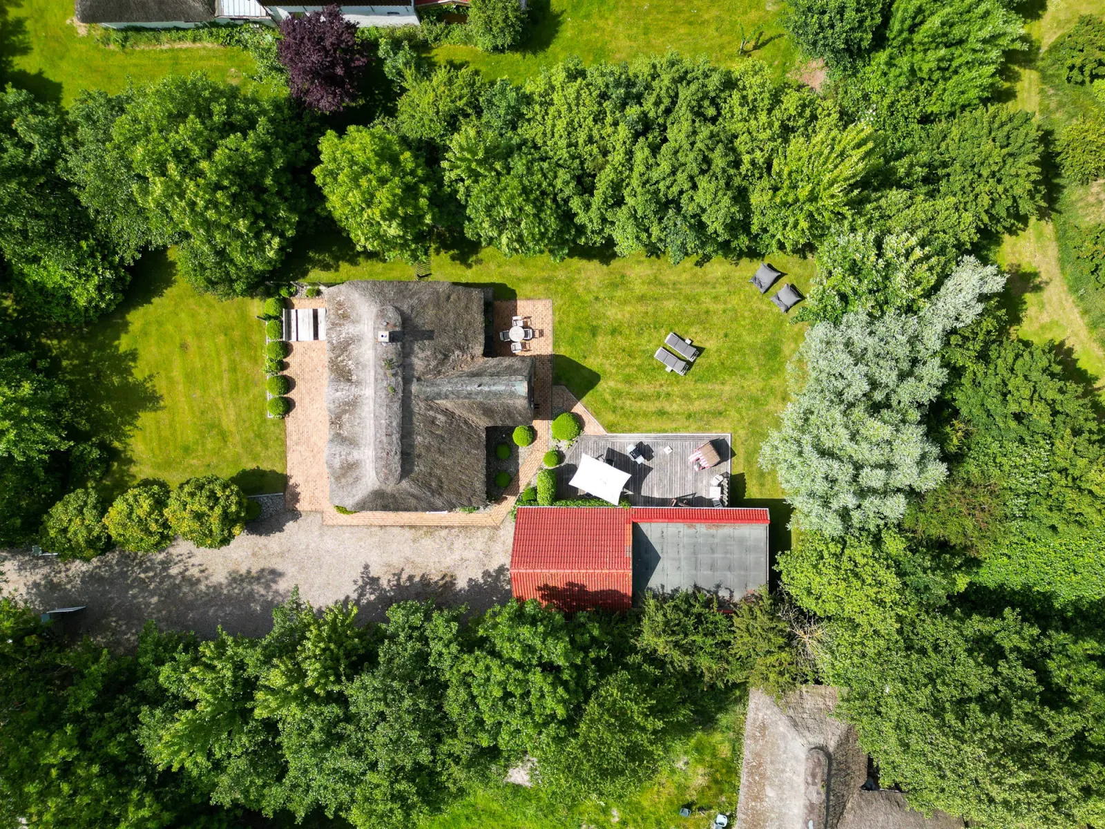Luftaufnahme von Reetdachhaus, Garten und Nebengebäude mit rotem Dach