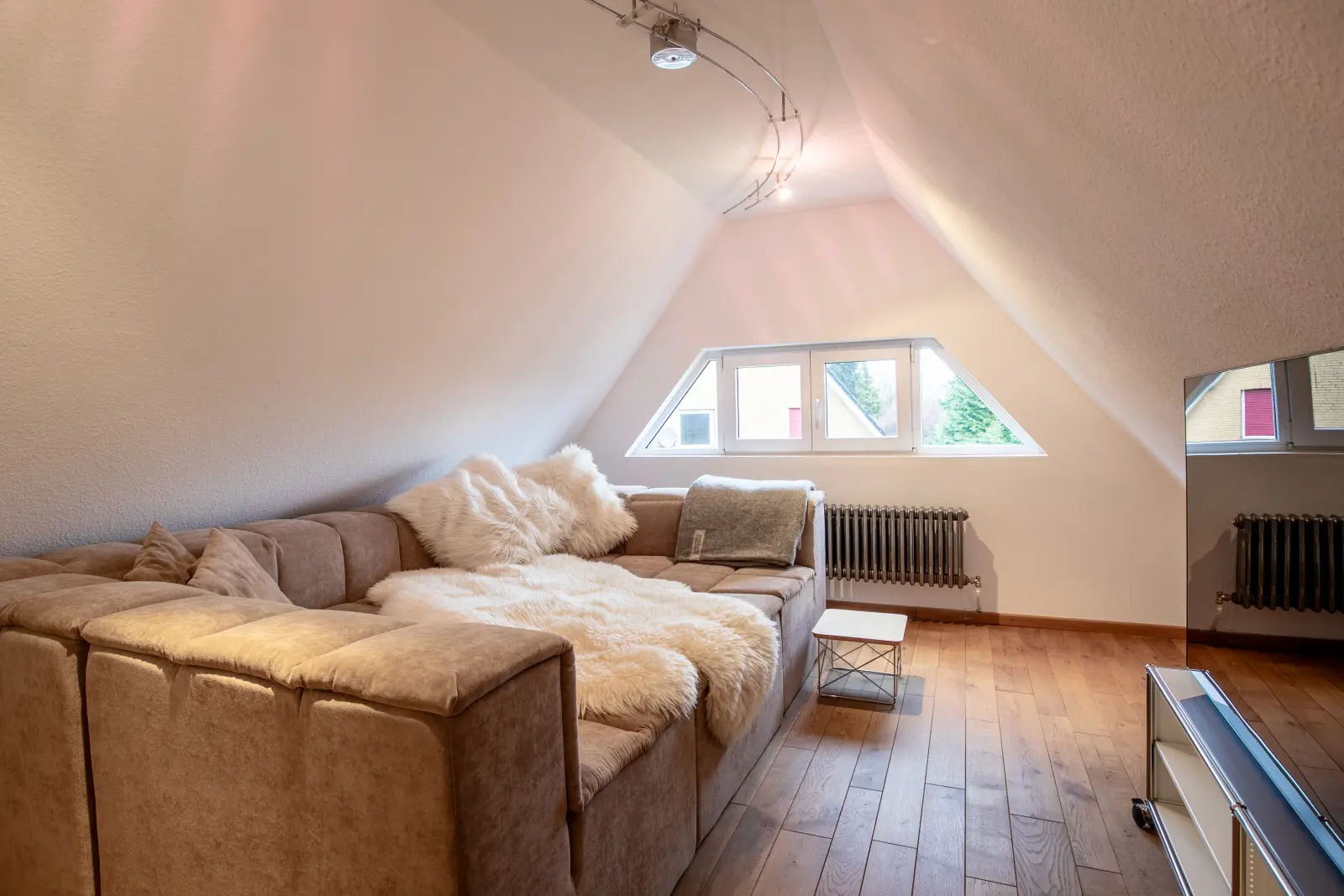 Sofa mit Felldecken unter der Dachschräge mit Giebelfenster