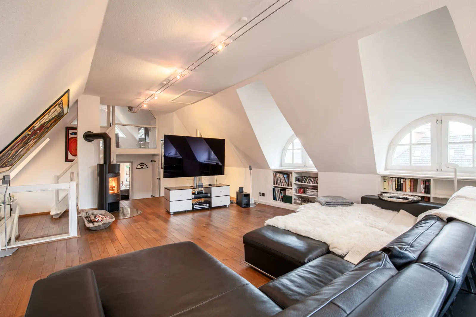 Offener Dachwohnraum mit Ledersofa, Kaminofen und Fernseher