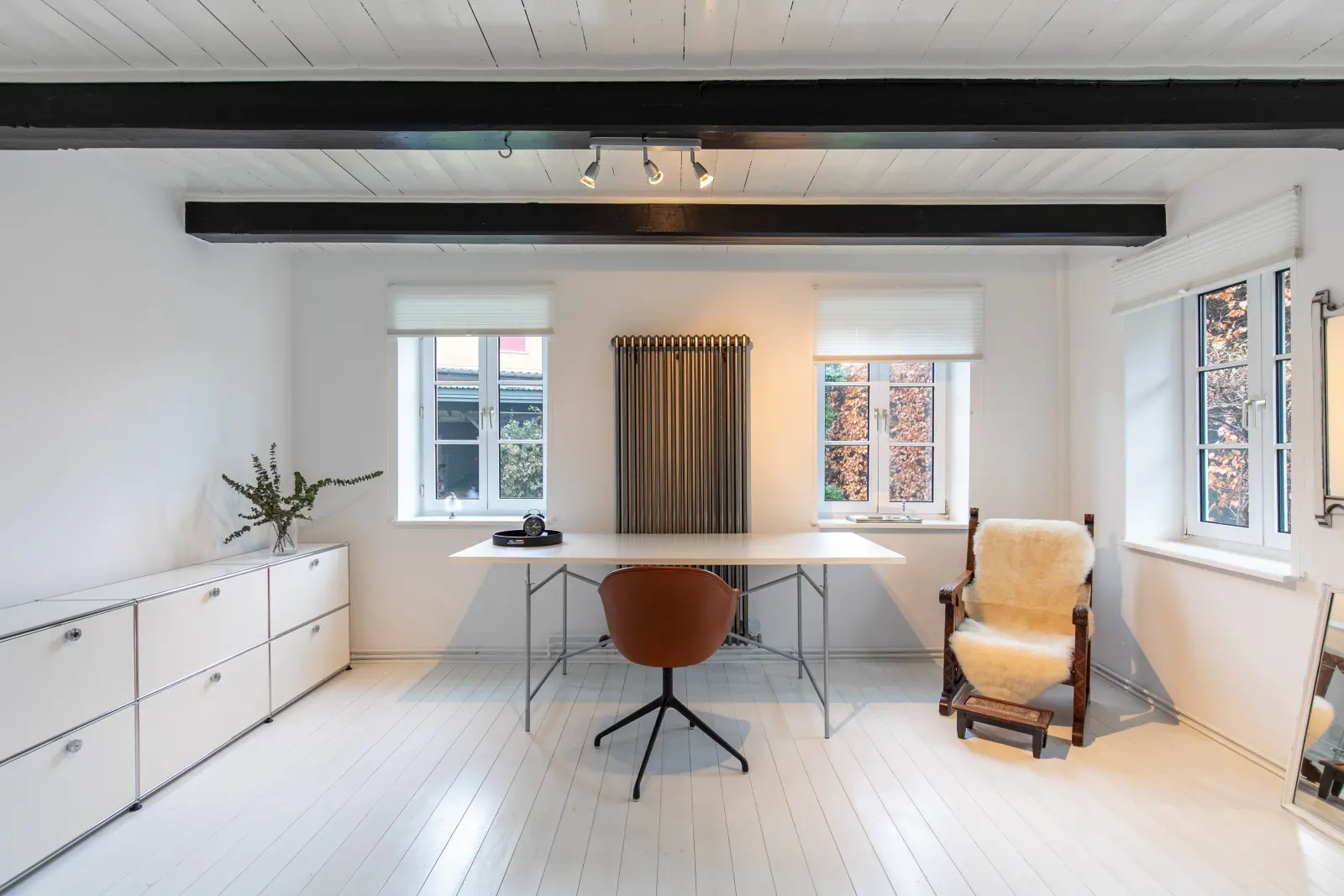 Arbeitszimmer mit Sideboard, Esstisch als Schreibtisch und Lederstuhl, weißer Dielenboden
