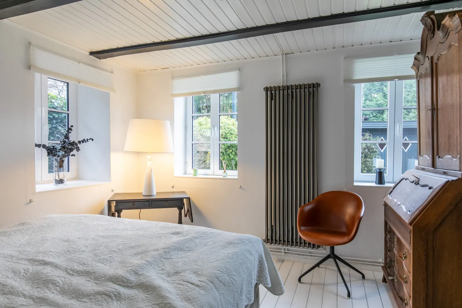 Gästezimmer mit Bett, Sekretär, Heizkörper und Fenstern zum Garten