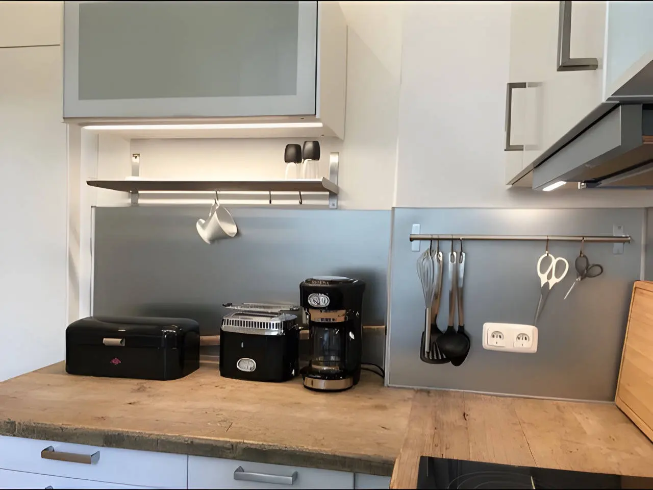 Küchenzeile mit Holzarbeitsplatte, Toaster, Kaffeemaschine und Brotkasten