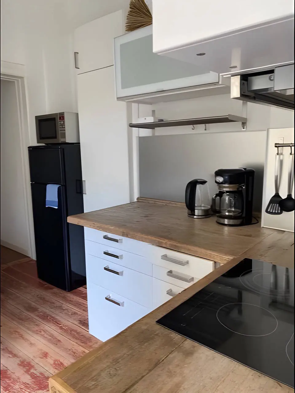 Küche mit Holzarbeitsplatte, Kühlschrank, Wasserkocher und Kaffeemaschine