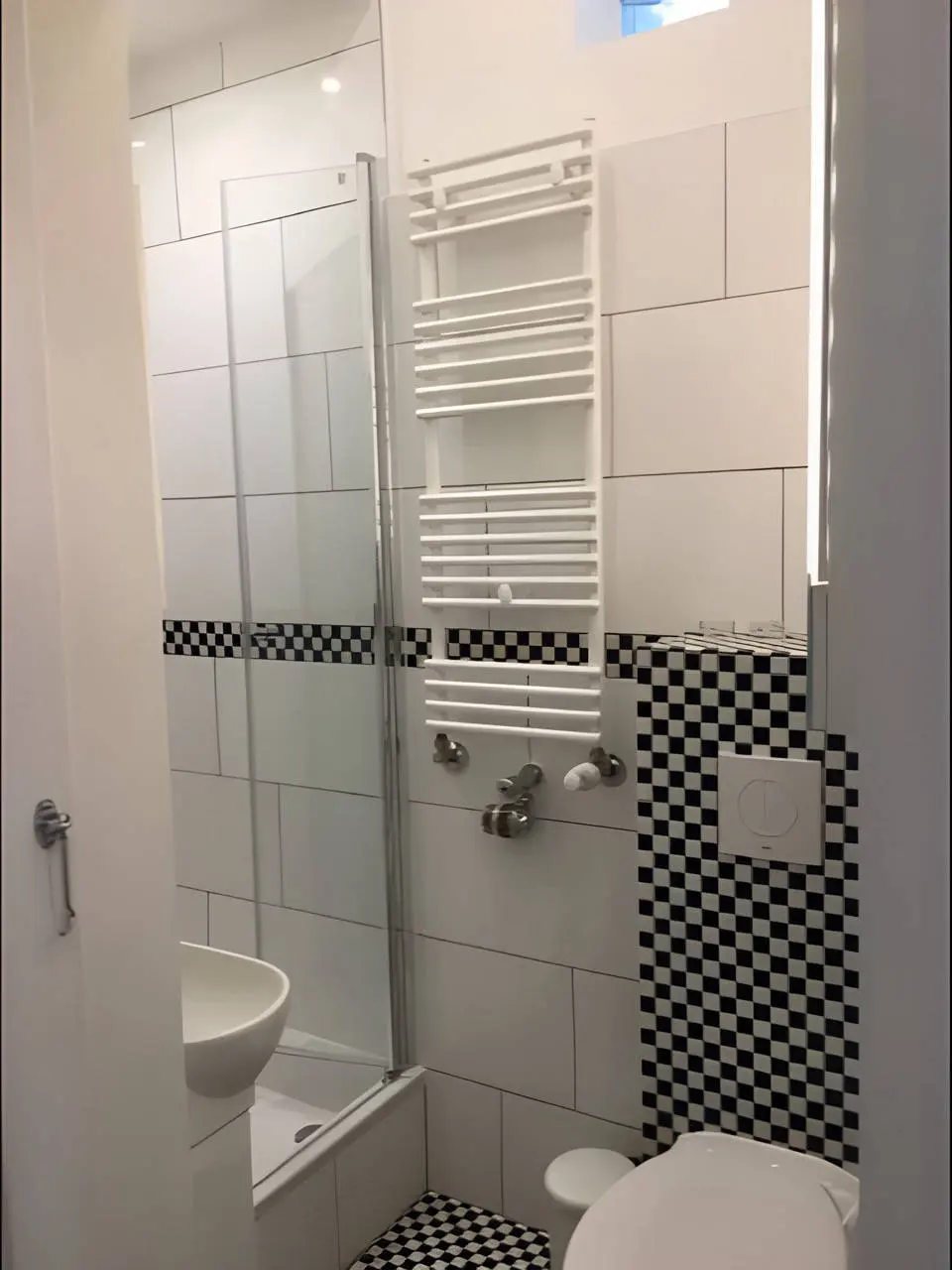 Duschbad mit Handtuchheizkörper, Glasdusche und Schachbrettfliesen