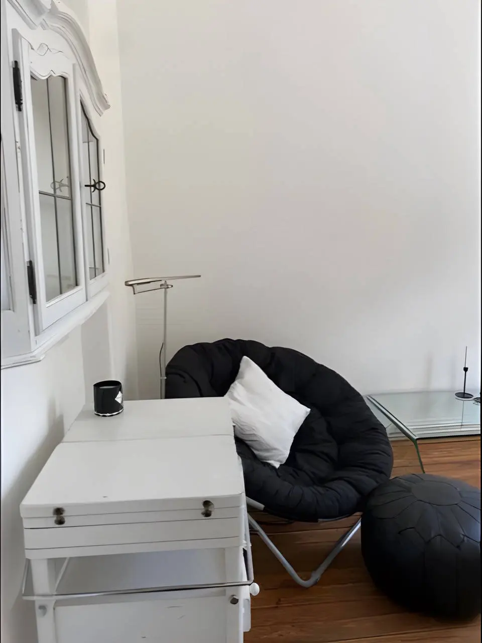 Lesesessel in Schwarz mit Pouf, Klapptisch und Glastisch in der Wohnzimmerecke