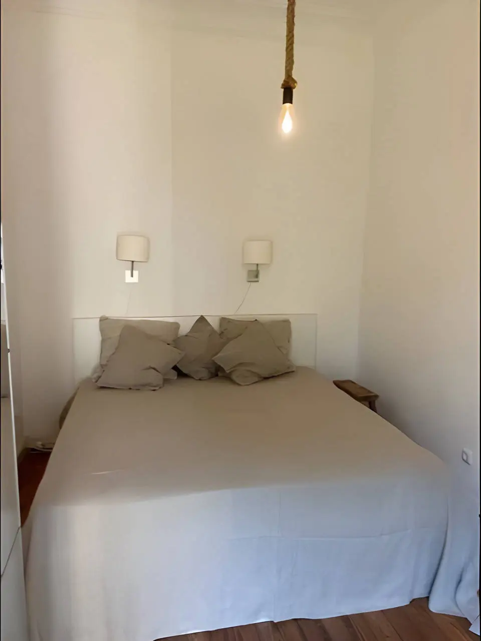 Schlafzimmer mit Doppelbett, Wandleuchten und Glühbirne an Seil