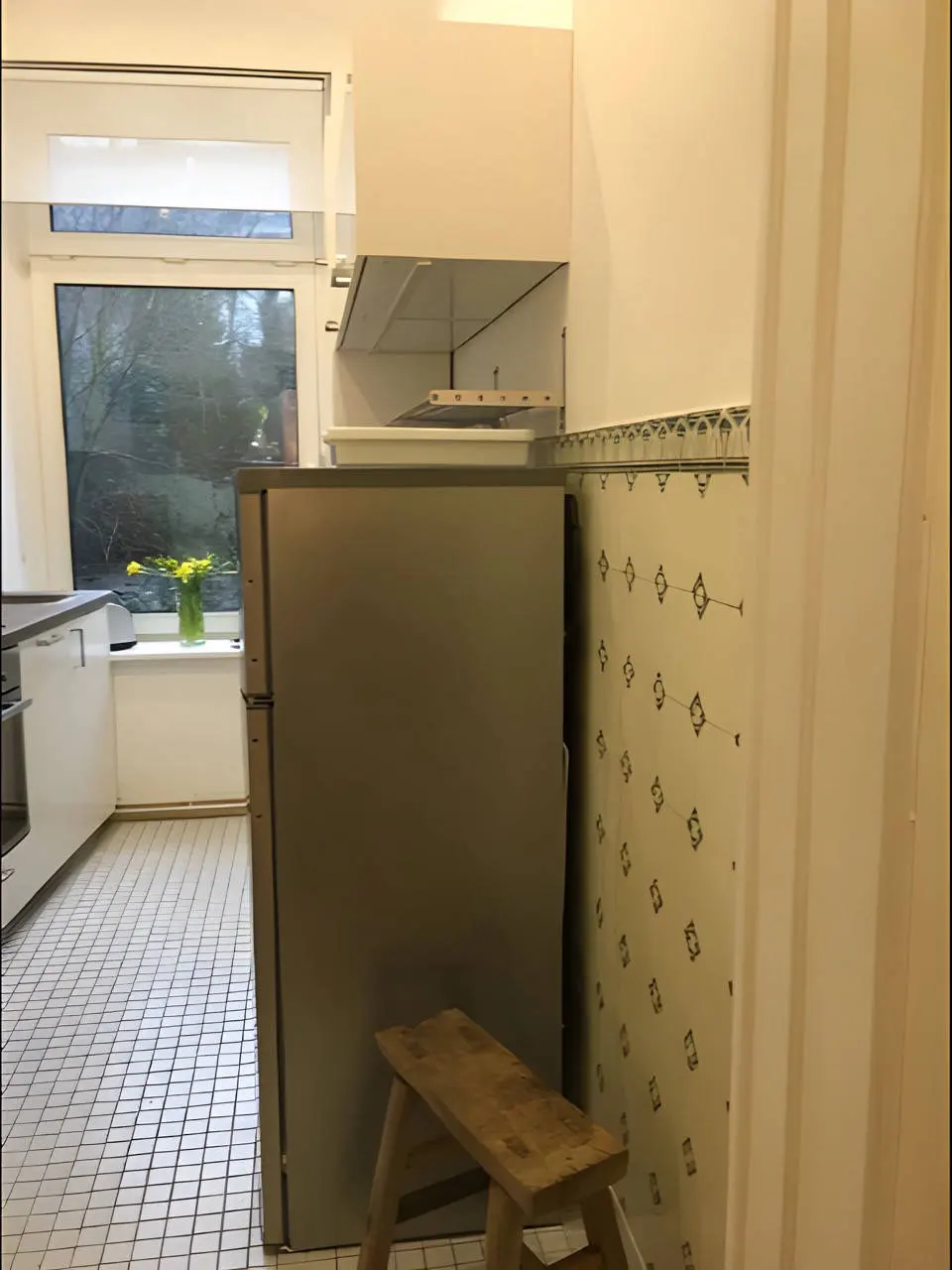 Küche mit Kühlschrank, Holzhocker und gemusterten Wandfliesen