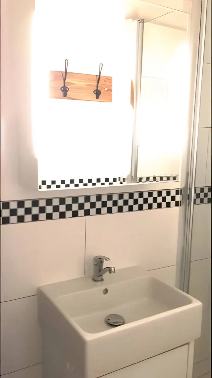 Waschbecken mit Armatur und Garderobenleiste im Bad mit Schachbrettborte