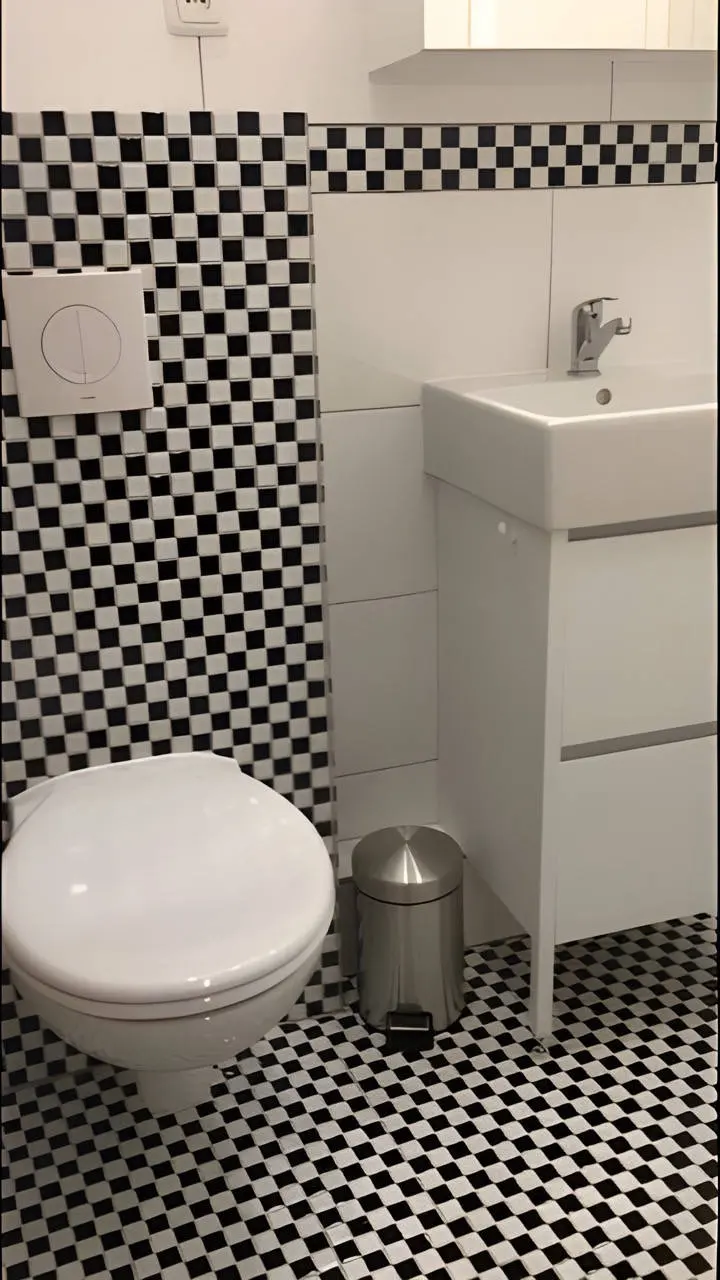 Wand-WC mit Waschtisch und schwarz-weißem Mosaikboden im Bad