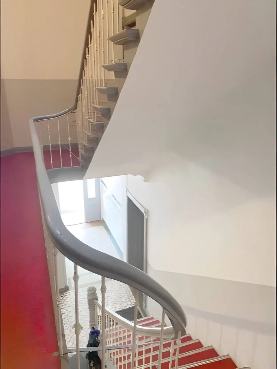 Treppenhaus mit rotem Läufer und geschwungenem Handlauf im Altbau