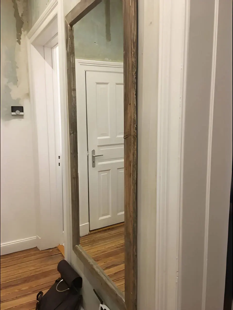 Flur mit Standspiegel und Blick auf weiße Wohnungstür