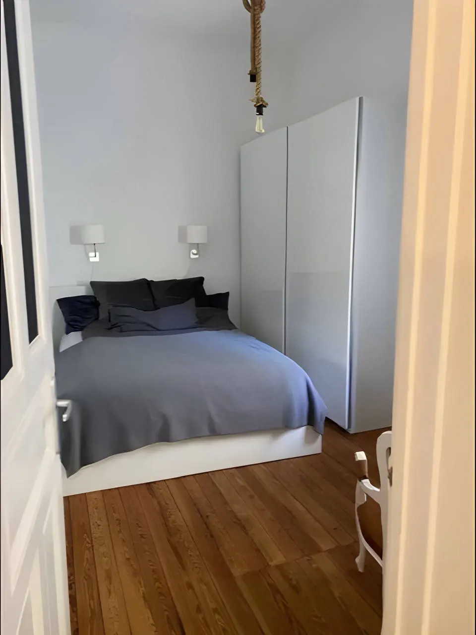 Schlafzimmer mit Doppelbett, blauer Bettwäsche und Schiebetürschrank