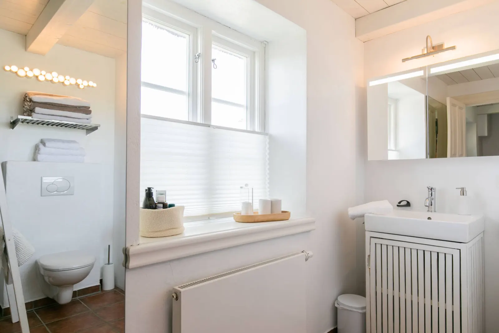 Waschbecken mit Spiegelschrank und Fensterbank im weißen Bad