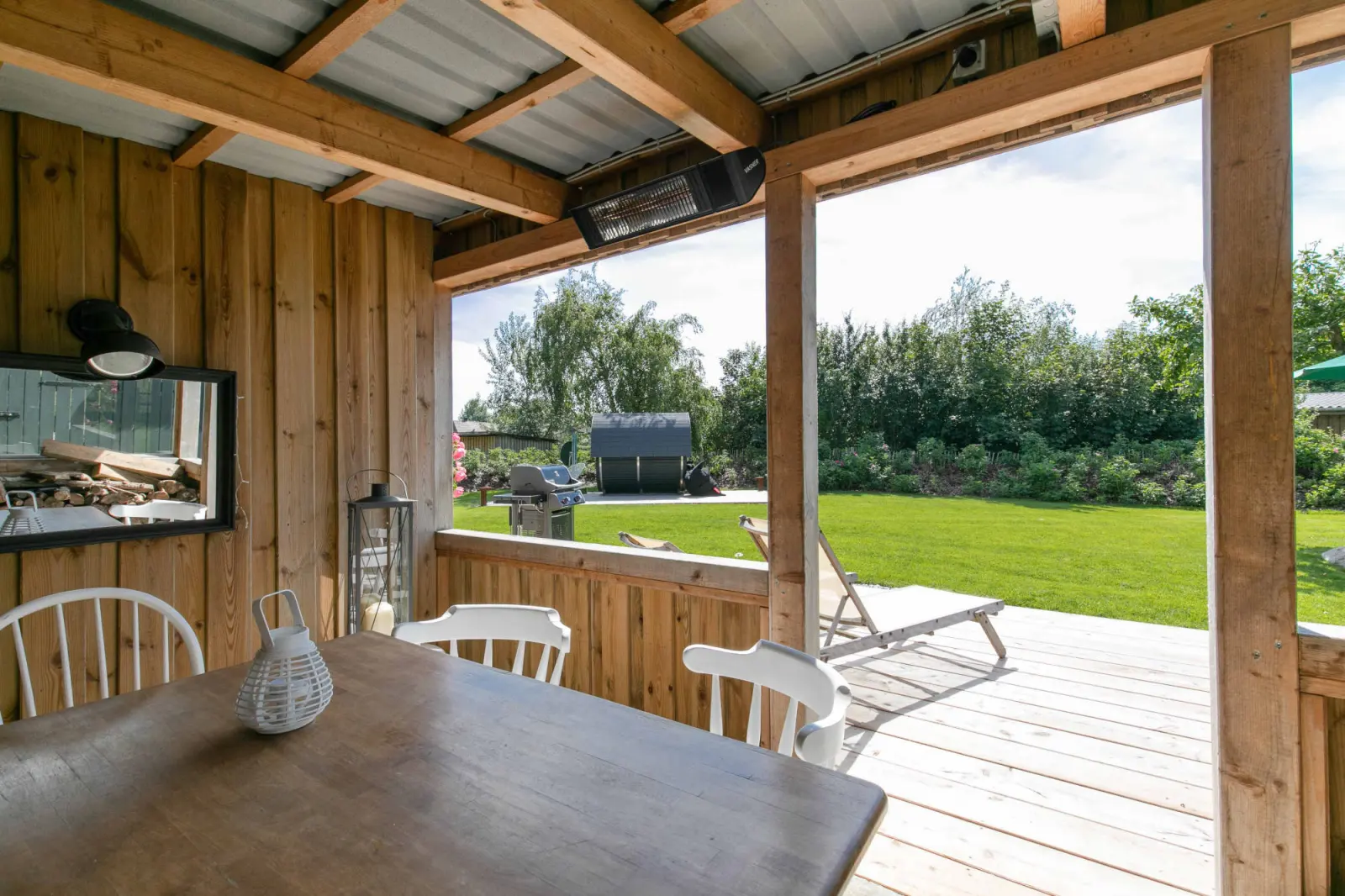 Blick aus dem Pavillon mit Tisch, Stühlen und Liege auf den Garten