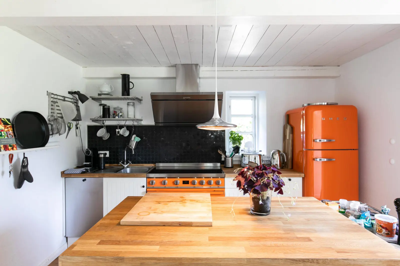 Küche mit Holzkochinsel, orangem Retro-Kühlschrank und Standherd
