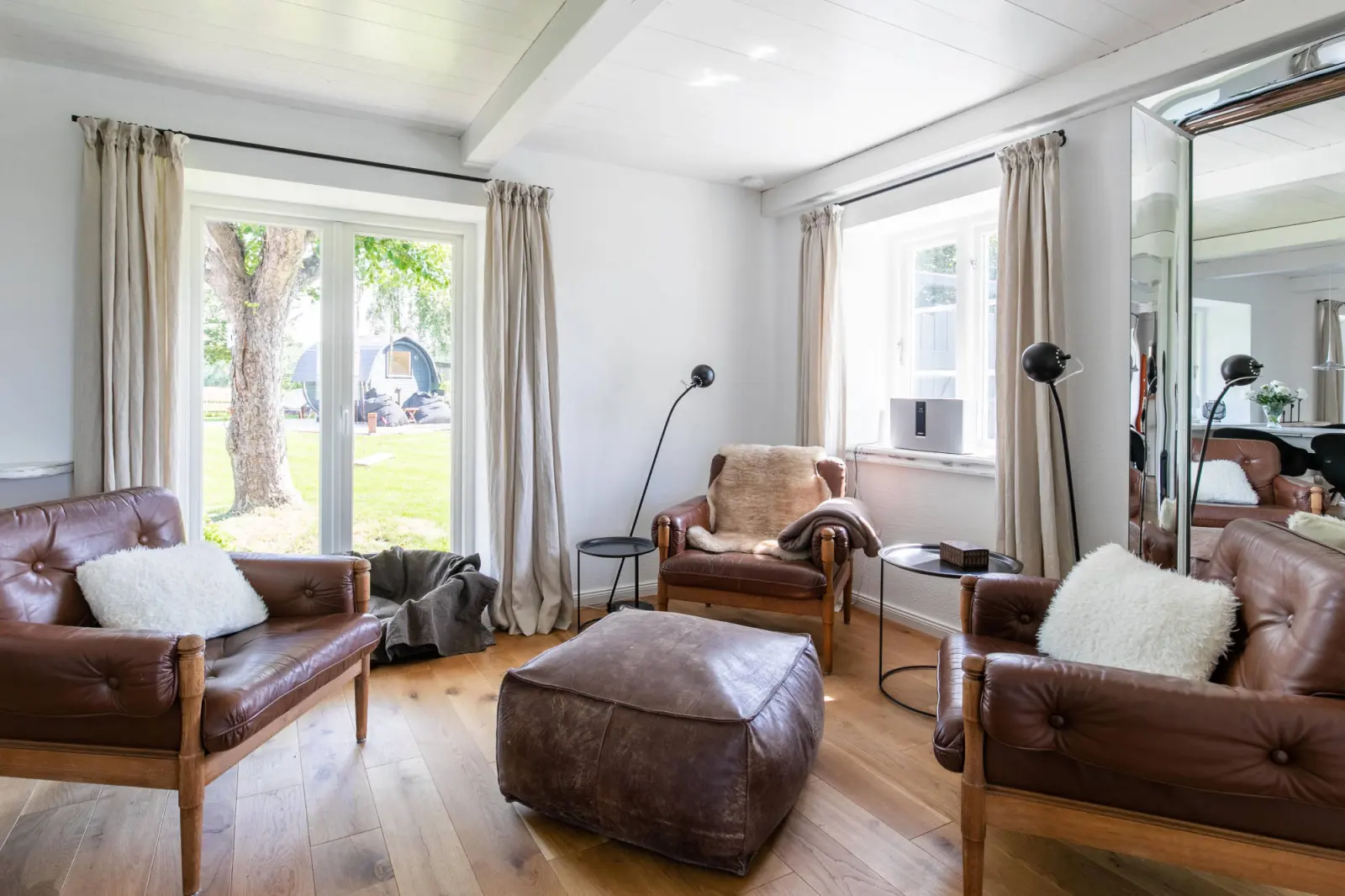 Sitzecke mit braunen Ledermöbeln, Lederpouf und Terrassentür
