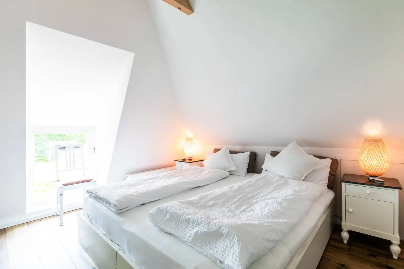 Doppelbett mit Nachttischen und Lampen, Fenster zum Garten im Dachgeschoss