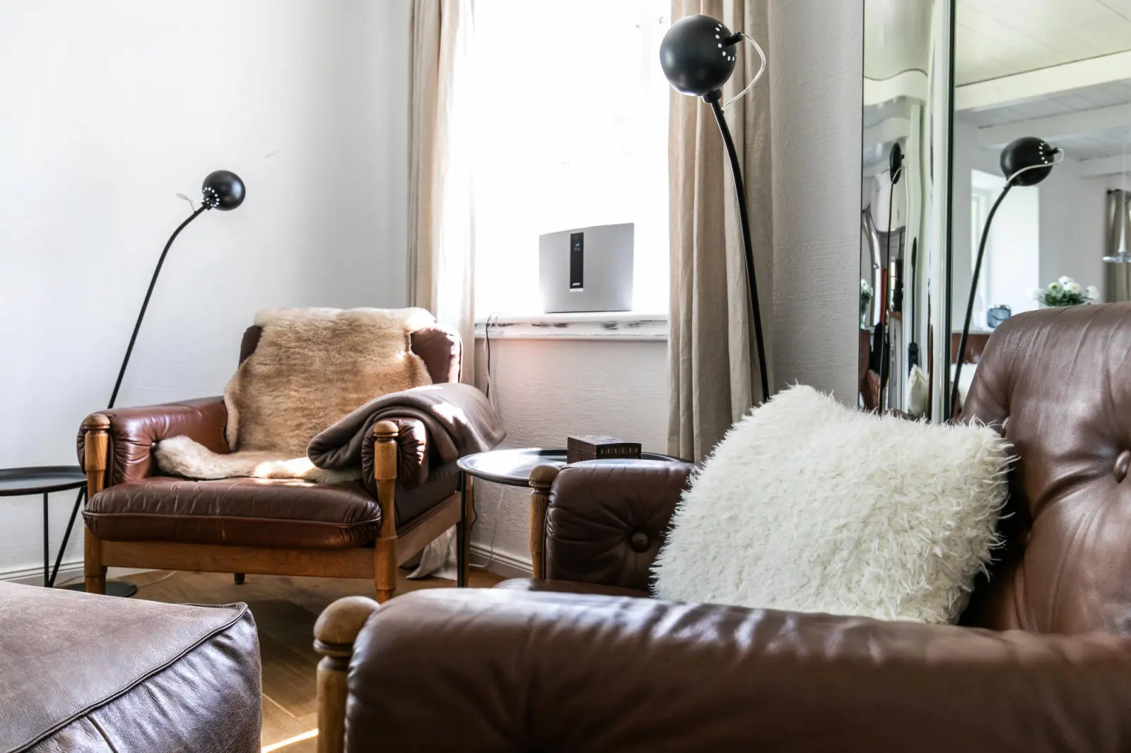 Ledersessel mit Fell, Stehlampe und Kissen in der Wohnzimmerecke