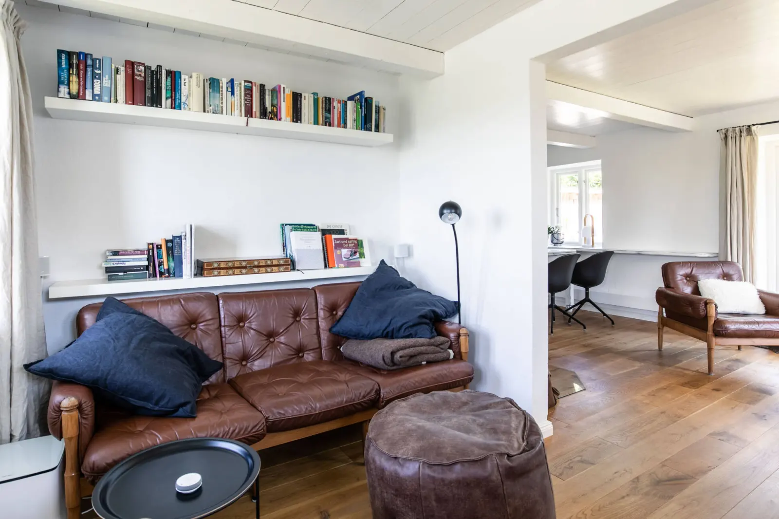 Ledersofa mit dunkelblauen Kissen, Bücherbord und Beistelltisch