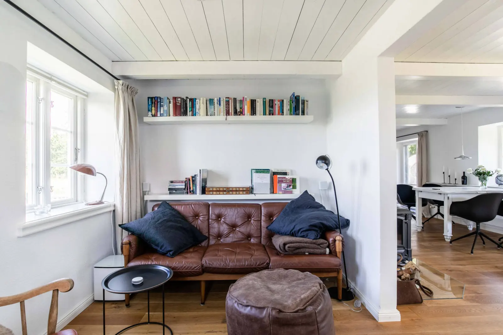 Wohnbereich mit Ledersofa, Pouf und Durchblick zum Essplatz