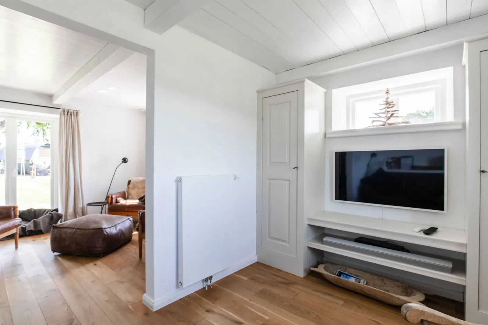 Fernseher in der Wandnische und Ledersessel im hellen Wohnraum
