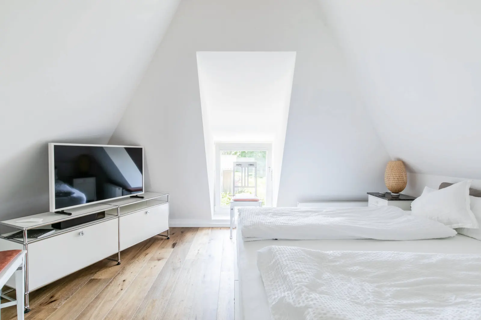 Schlafzimmer mit Fernseher auf Sideboard, Doppelbett und Dachfenster