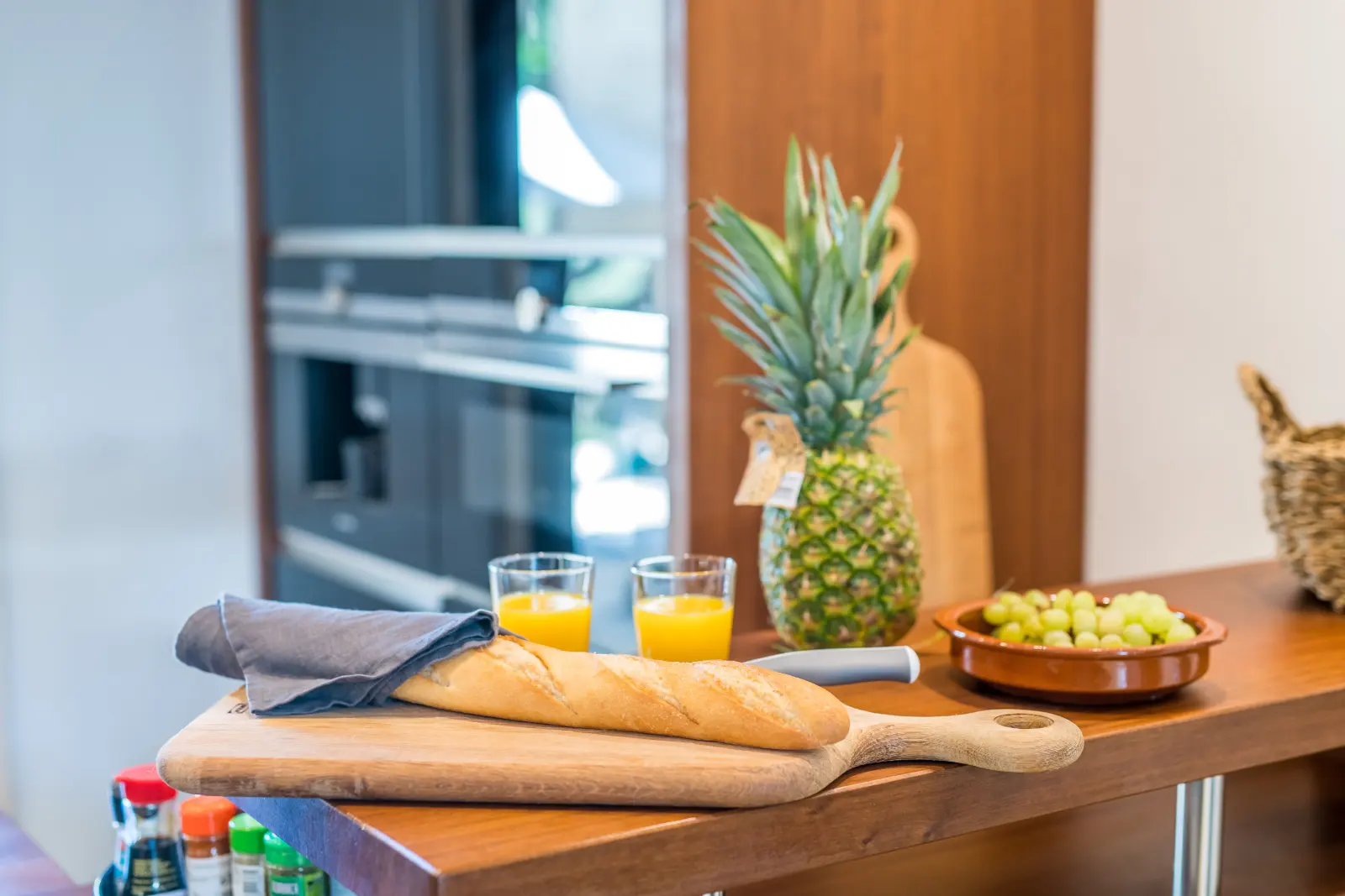 Küchenzeile mit dunklen Glasfronten, Holzinsel und Obstschale mit Ananas