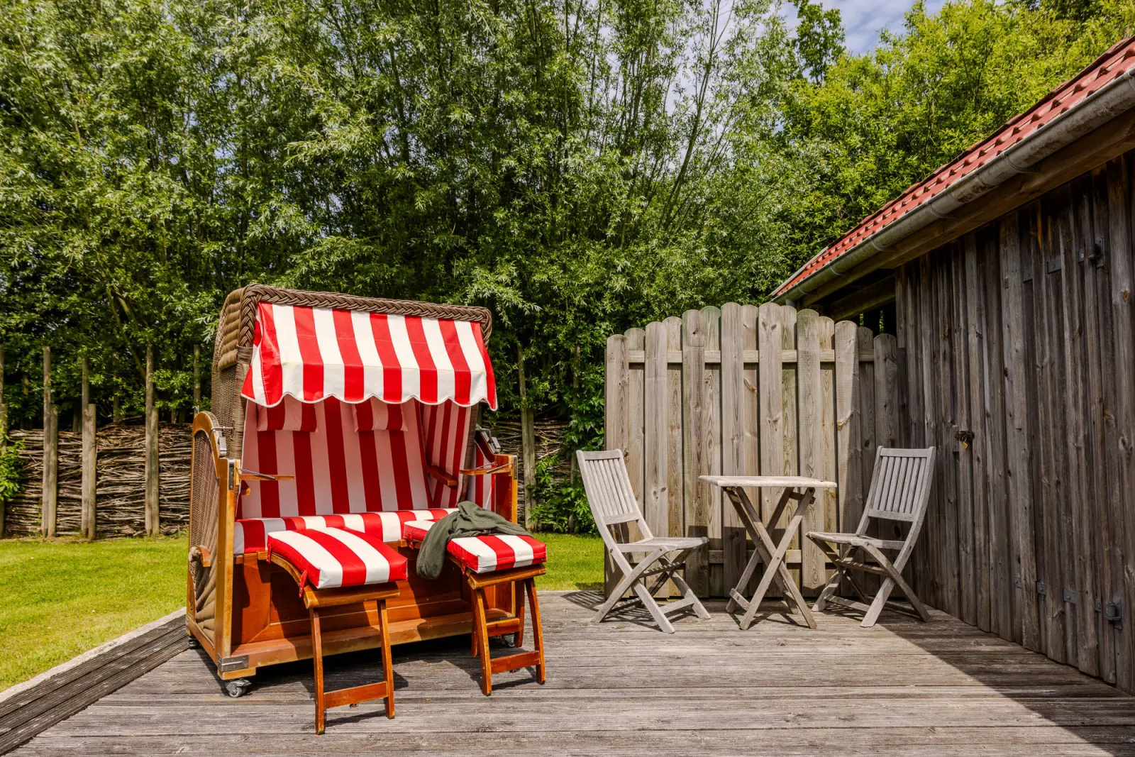 Rot-weiß gestreifter Strandkorb und Klappstühle auf der Holzterrasse