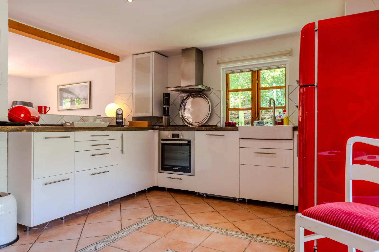Einbauküche in L-Form mit Backofen, Dunstabzug und rotem Kühlschrank
