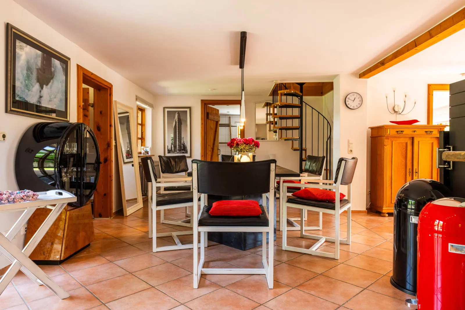 Esstisch mit schwarzen Stühlen, Wendeltreppe und Holzschrank im Hintergrund