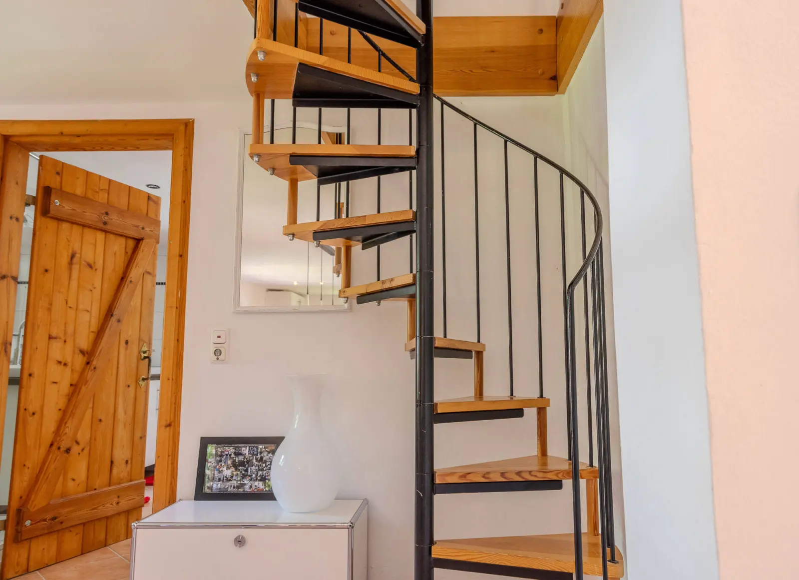 Wendeltreppe mit Holzstufen neben einer Holztür im Flur
