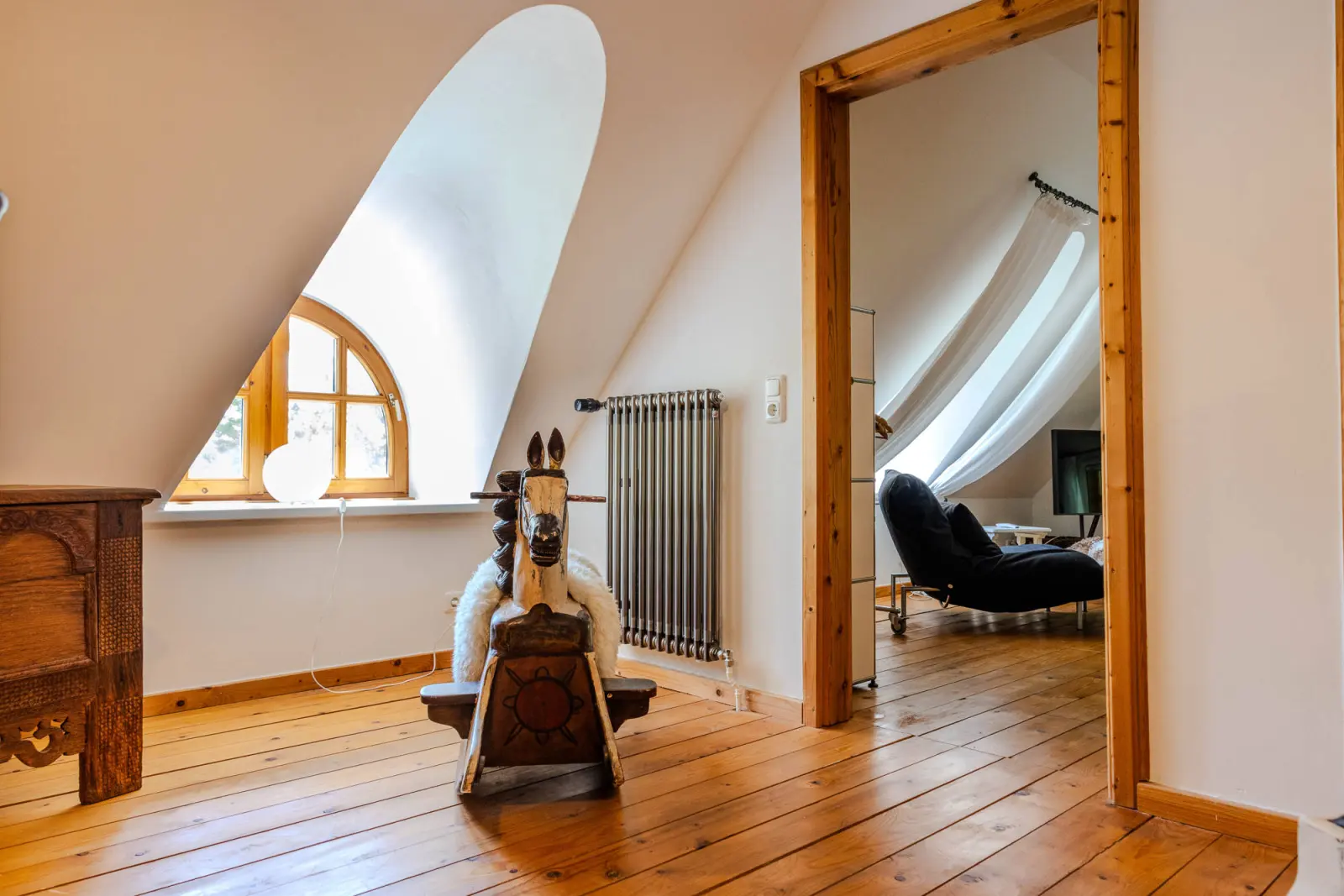 Dachgeschoss-Flur mit Rundbogenfenster, Schaukelpferd und Dielenboden