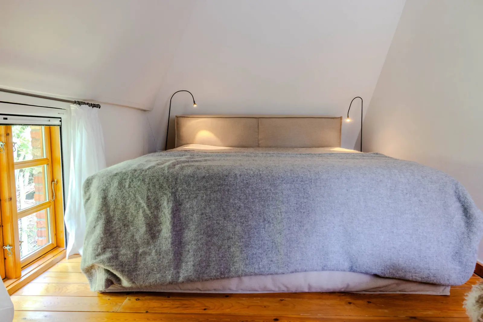 Doppelbett im Dachgeschoss mit Leselampen und Holzdielenboden