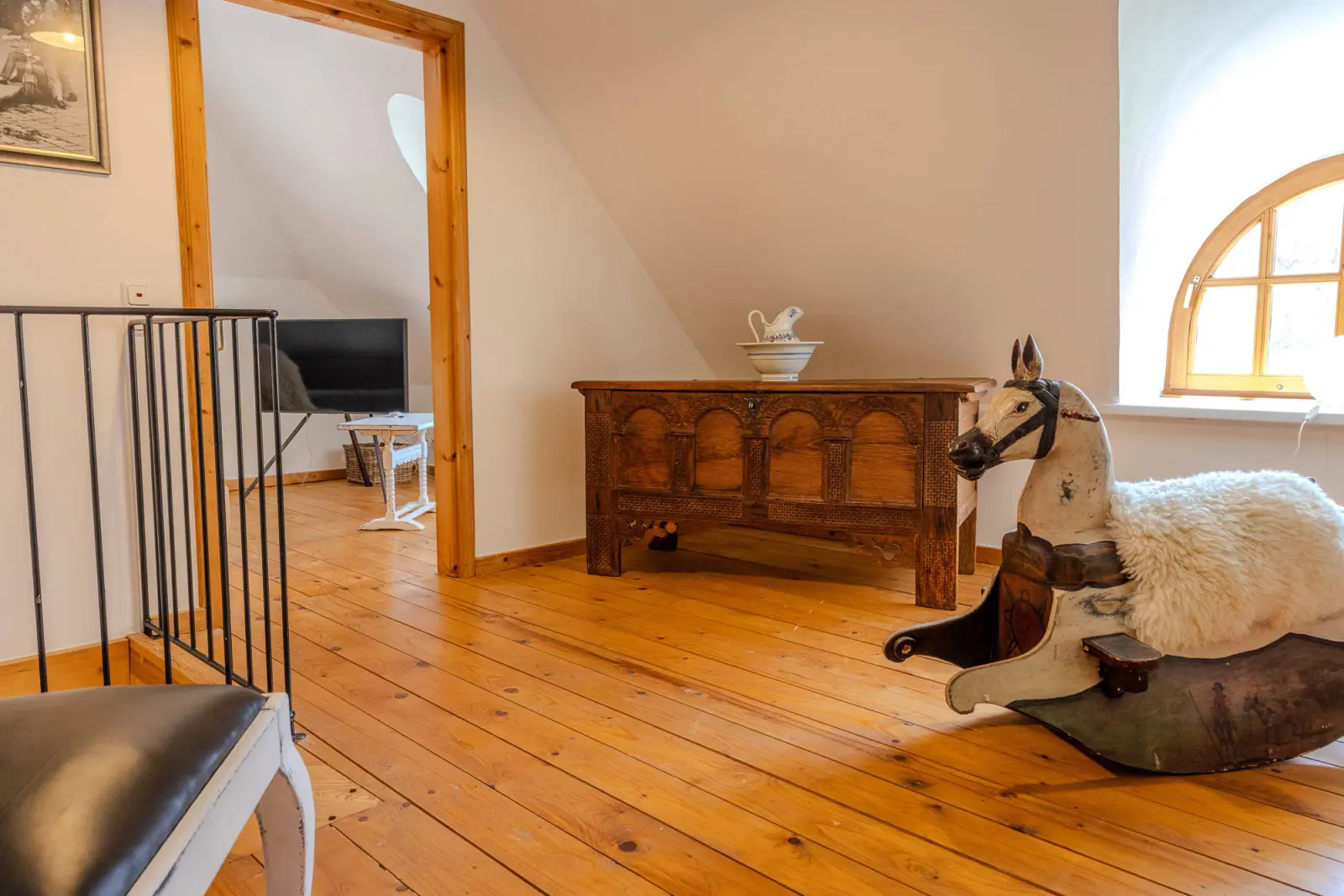 Dachgeschoss mit Holzkommode, Schaukelpferd und Treppengeländer