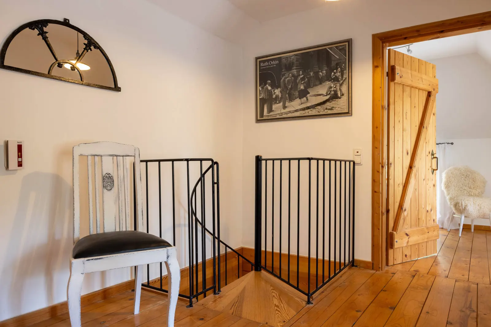 Treppenabgang mit Geländer, Stuhl und Holztür im Obergeschoss