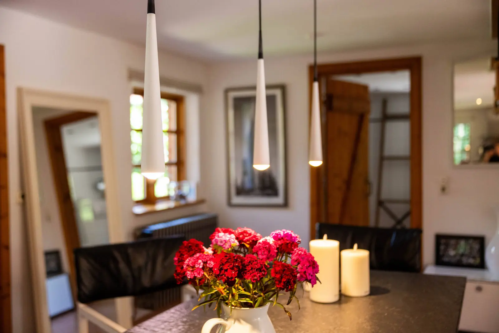 Blumenstrauß auf dem Esstisch mit Kerzen und Pendelleuchten im Wohnraum