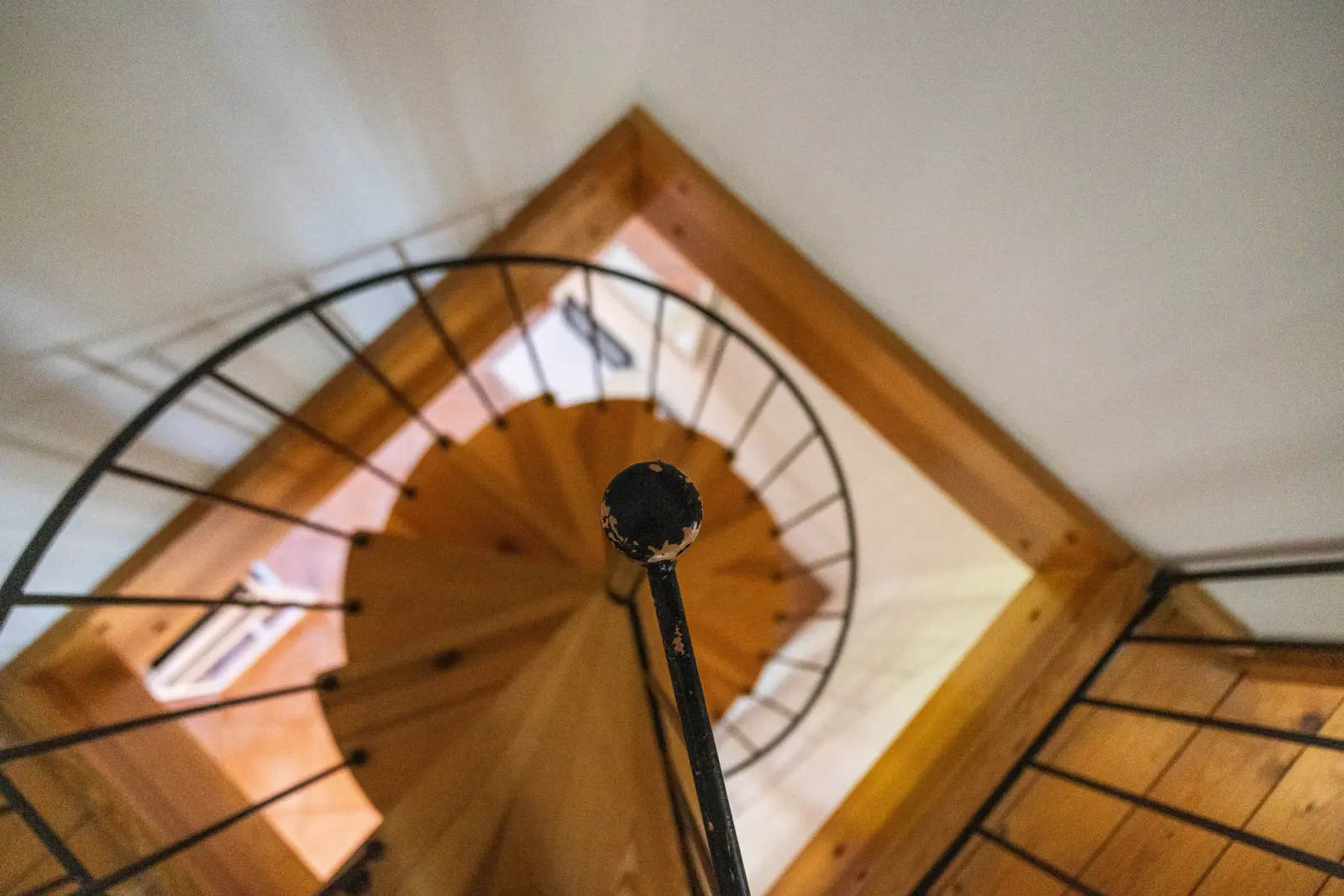 Blick von oben auf die Wendeltreppe mit Holzstufen und Geländer