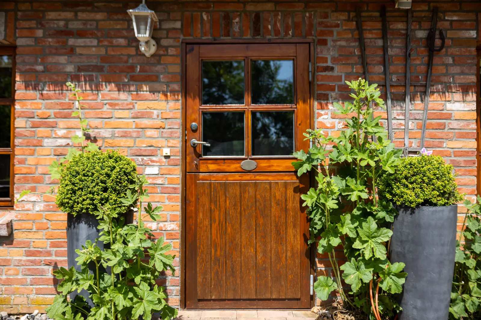 Holzhaustür mit Laterne, Pflanzkübeln und Backsteinwand