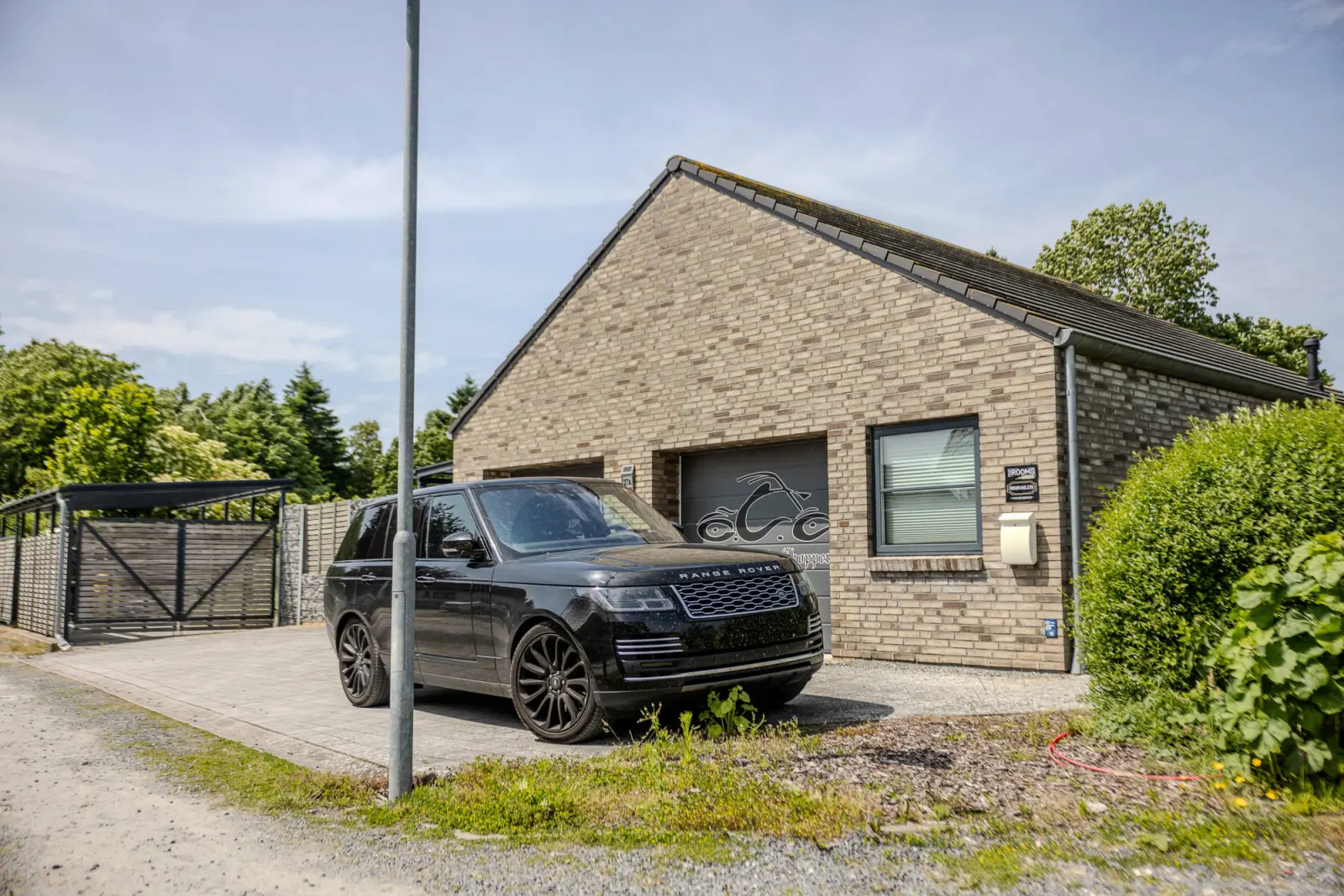 Giebelseite mit Garage und Fenster, davor geparktes Auto auf Pflaster