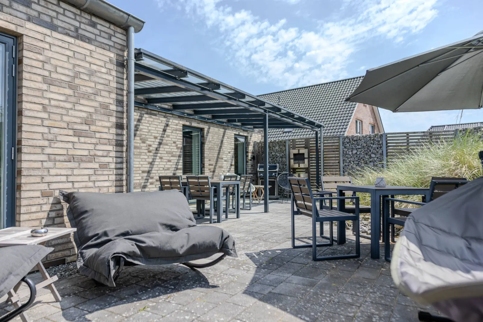 Sitzplatz mit Schaukel-Sitzsack, Tischgruppe und Sonnenschirm an der Terrasse