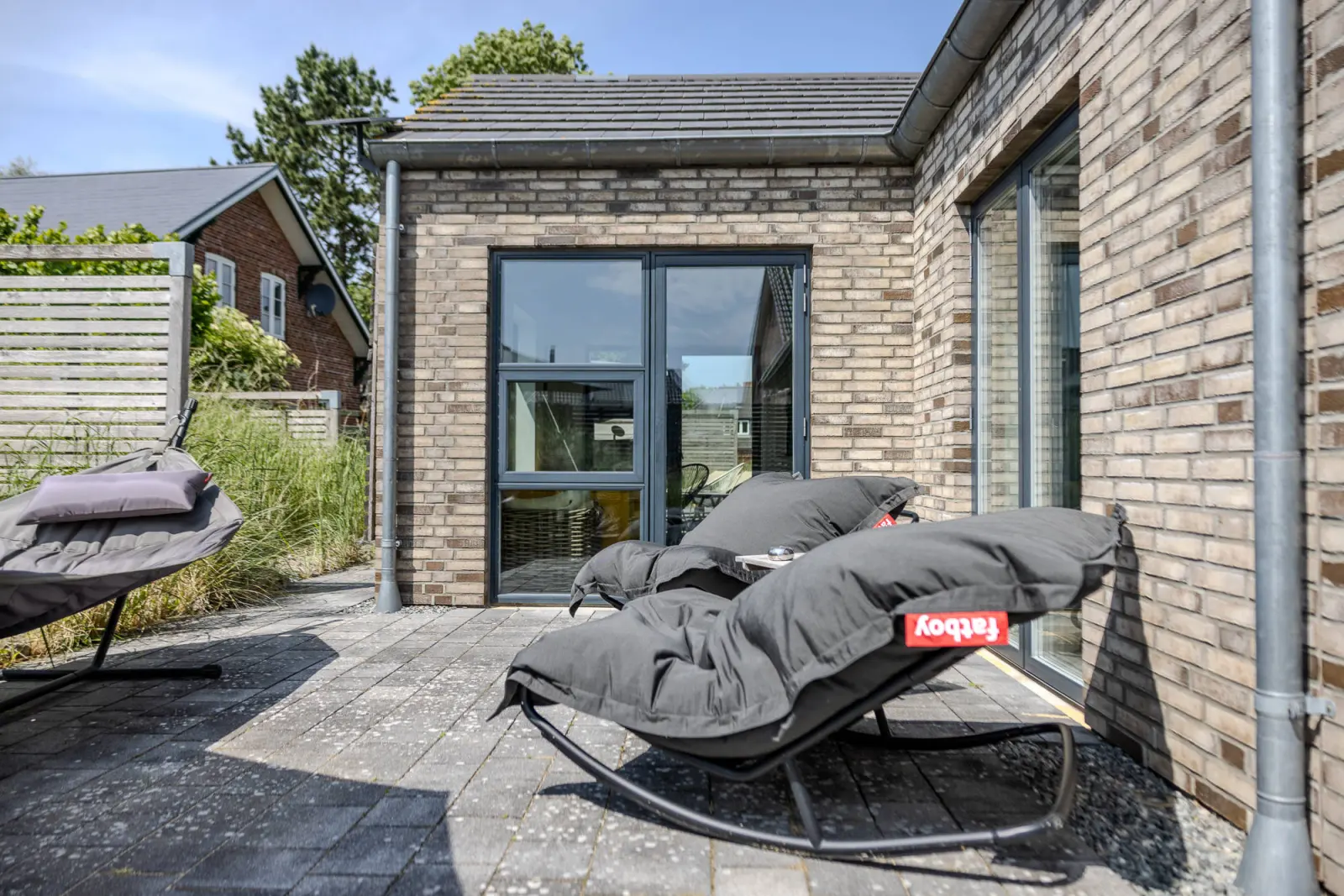 Schaukelnde Sitzsäcke auf der Terrasse vor Glasfront des Anbaus