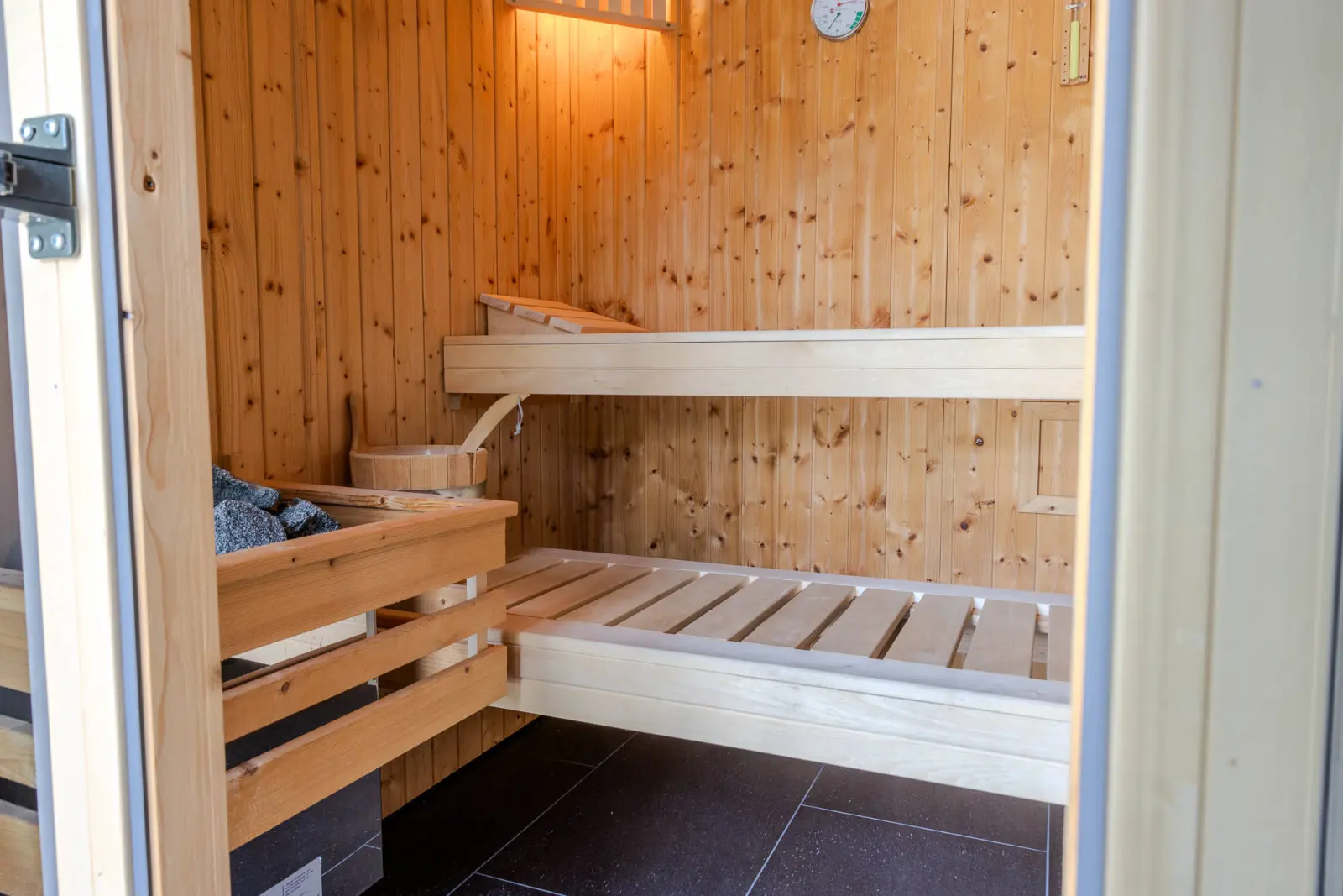 Sauna mit zweistufiger Holzbank und Saunaeimer