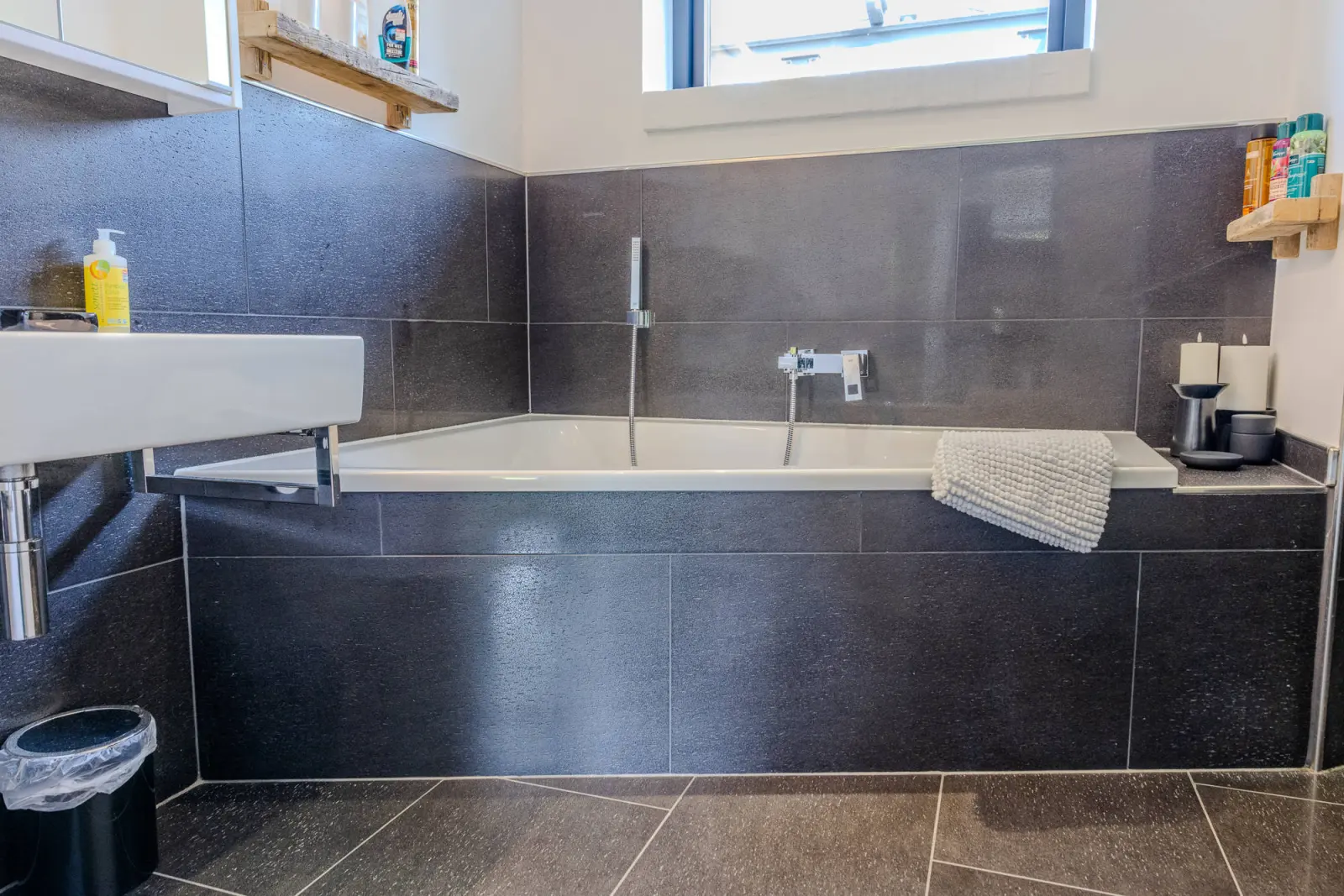 Bad mit Einbauwanne, Waschbecken und dunklen Natursteinfliesen