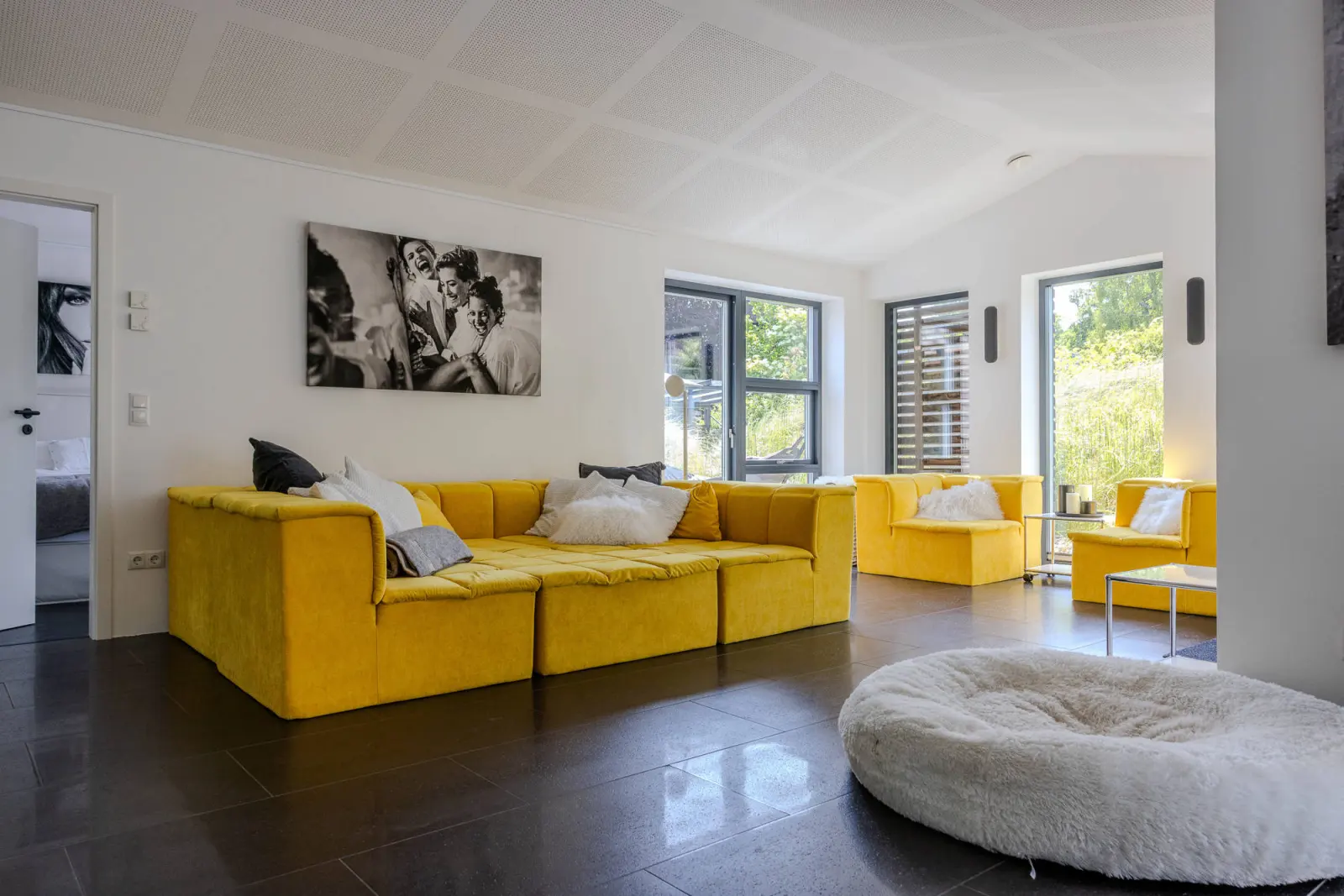 Wohnbereich mit gelbem Modulsofa, Fotokunst und Fenstertüren