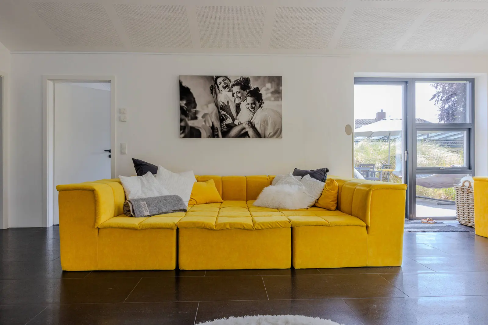 Gelbes Sofa vor Schwarz-Weiß-Fotokunst, Fenster zur Terrasse