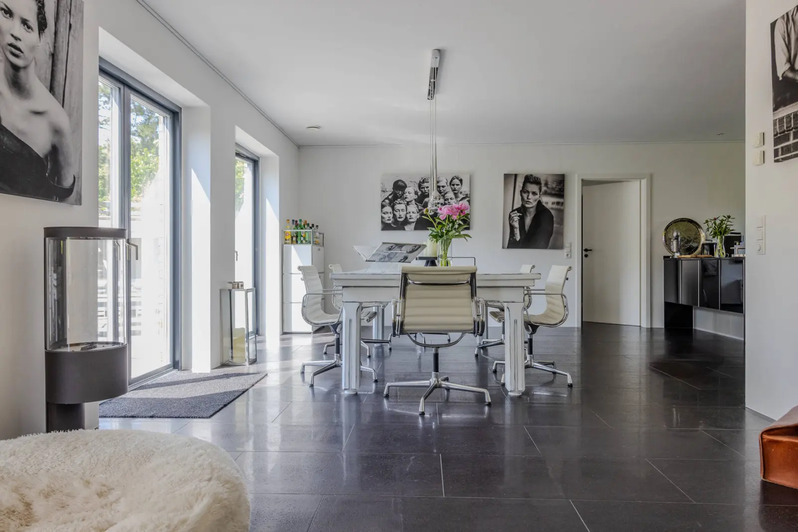 Esstisch mit Bürostühlen und Blumenstrauß, Kaminofen am Fenster